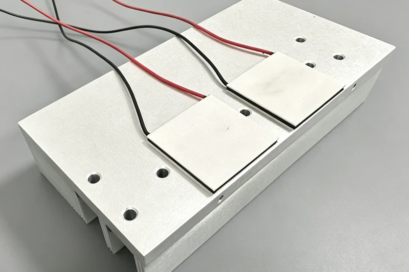 Two white TEC modules mounted on aluminum plate with wires